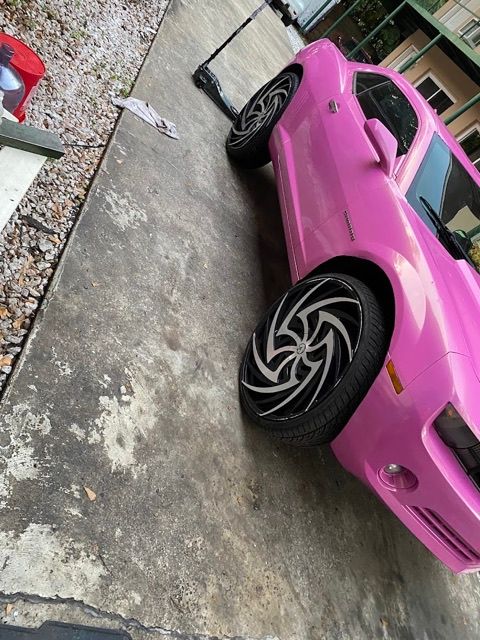 Pink Chevrolet Camaro on custom wheels and low-profile tires in a Tallahassee driveway, with a floor jack beside it